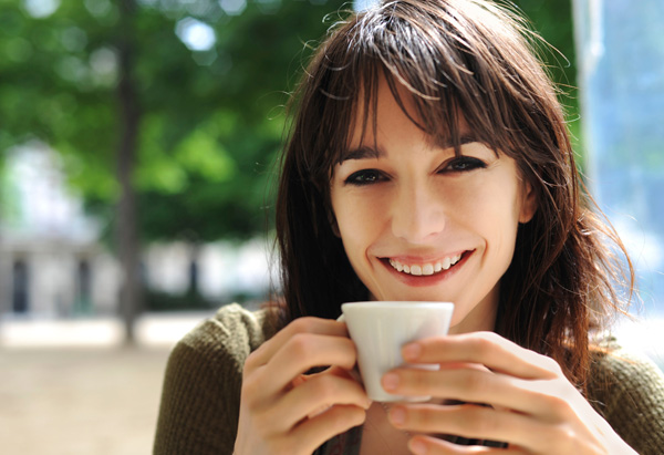 bella ragazza che sorride tenendo in mano tazza di caffè